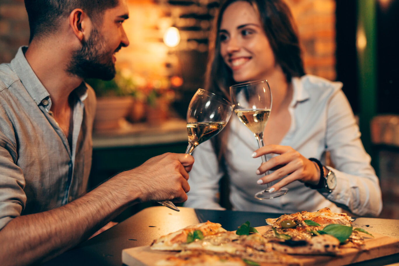 young couple making toast with wine, at home in garden, evening